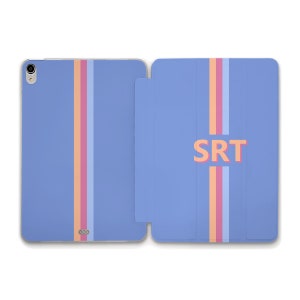 Peut inclure: Une coque pour iPad bleue avec une bande rose, orange et bleu clair au centre. La coque porte les lettres "SRT" en orange au dos.