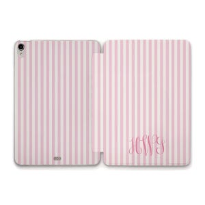May include: Pink and white striped tablet case with a monogram. The case is open, revealing the interior and exterior design. The cover features a vertical stripe pattern and a monogram in a matching pink hue.
