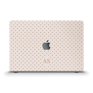 May include: A beige laptop cover featuring a polka dot design. The Apple logo is centrally placed, with the initials "AS" beneath. The cover is designed to fit a laptop.
