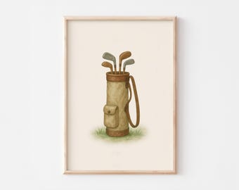 Puede incluir: Ilustración en acuarela de una bolsa de golf con palos. La bolsa es de color beige con una correa y un bolsillo marrones. Los palos son plateados y marrones. La imagen está sobre un fondo crema y enmarcada en un marco de madera clara.
