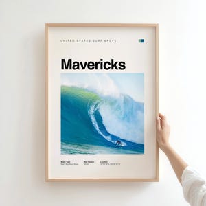 May include: A framed poster featuring a large wave with a surfer. The poster has the word "Mavericks" in bold black letters. The top of the poster reads "UNITED STATES SURF SPOTS". The frame is a light brown color.