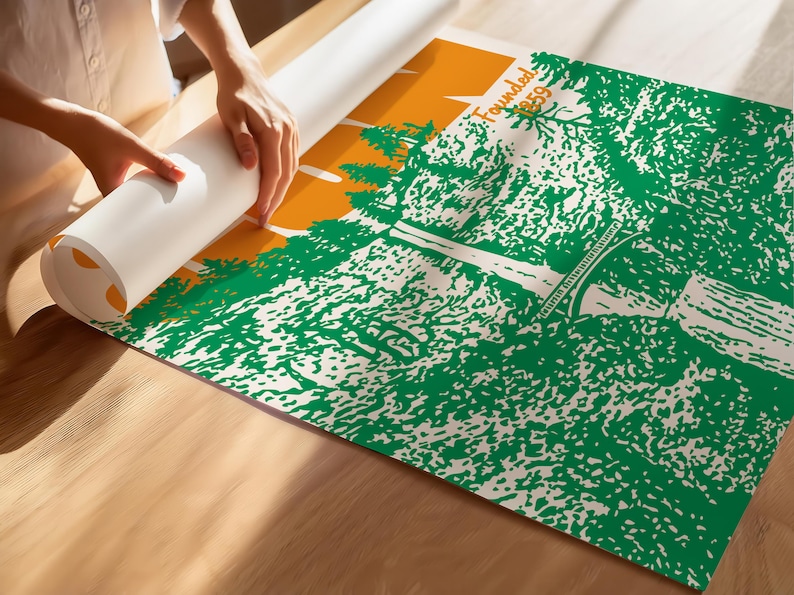 May include: A person unrolling a poster with a green and white landscape design, an orange sky, and the text "Founded 1859". The poster is on a wooden surface.