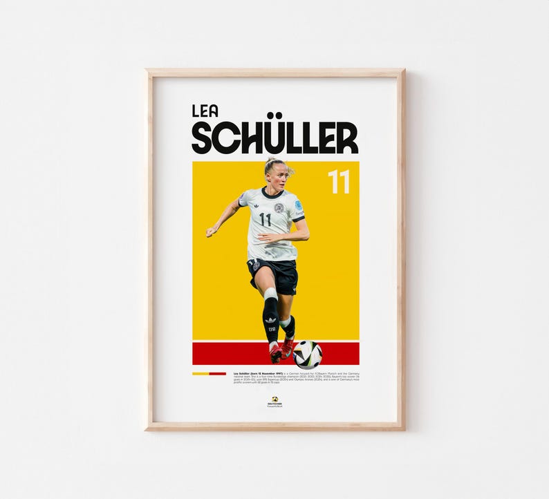 May include: Framed poster of a soccer player in a white and black uniform, with the name "LEA SCH&Uuml;LLER" in bold black letters. The number "11" is displayed. The background is yellow with red and black stripes at the bottom.
