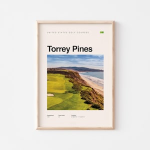May include: A framed print featuring a golf course landscape at Torrey Pines. The print includes the text "Torrey Pines" in bold black letters, with additional text at the top and bottom. The image shows a green golf course next to a beach and ocean.