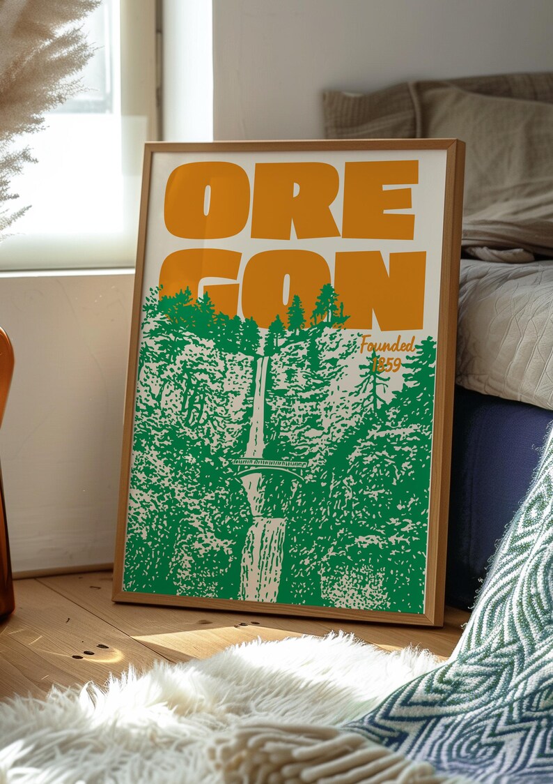 May include: Framed poster featuring the word "OREGON" in large orange letters above a green and white illustration of a waterfall and forest. The text "Founded 1859" is also present. The poster is in a wooden frame.