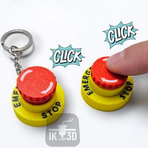 Puede incluir: Un llavero con botón de parada de emergencia amarillo y rojo y un botón que se está presionando. El botón tiene las palabras "PARADA DE EMERGENCIA" impresas. La palabra "CLICK" está en una burbuja de diálogo encima de los botones. El logotipo "IK 3D" también es visible.