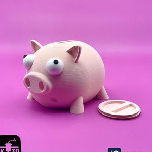 Pode incluir: Um cofrinho rosa em forma de porco com grandes olhos saltados brancos e uma fenda no topo para moedas. O cofrinho está sentado em uma superfície rosa com sua tampa ao lado.