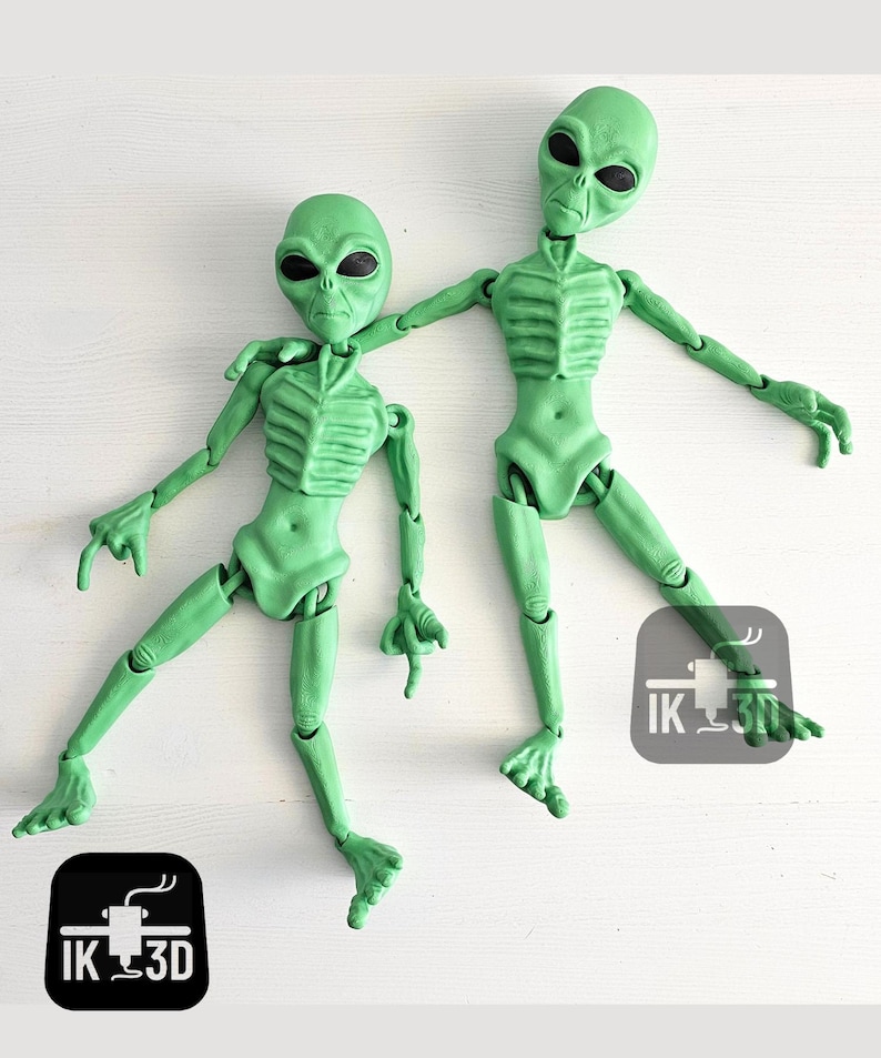 Puede incluir: Dos figuras alien&iacute;genas articuladas de color verde con cabezas grandes y ojos grandes. Las figuras est&aacute;n posadas de forma din&aacute;mica, con un brazo de una figura apoyado en el hombro de la otra. Las figuras est&aacute;n hechas de pl&aacute;stico liso verde.