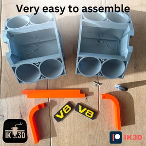 May include: A flat-pack, gray plastic model kit of a V8 engine. The kit is partially assembled and includes orange plastic parts, two black and yellow V8 labels, and small screws. The text "Very easy to assemble" is visible in the image.