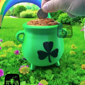 May include: A green pot shaped like a cauldron with a shamrock design and gold coins inside. The pot is sitting on green grass with pink and yellow flowers. A hand is dropping a gold coin into the pot.