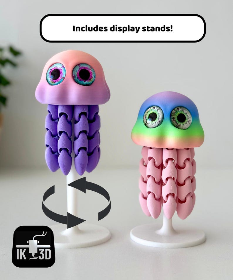 May include: Two colorful, 3D-printed jellyfish sculptures with display stands. One jellyfish is pink and purple, the other is pink and rainbow-colored. The text "Includes display stands!" is above the jellyfish.