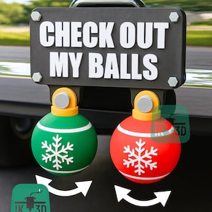 May include: A black sign with the text "CHECK OUT MY BALLS" in white, mounted above two Christmas ornament-shaped decorations. One ornament is green with a white snowflake, the other is red with a white snowflake.