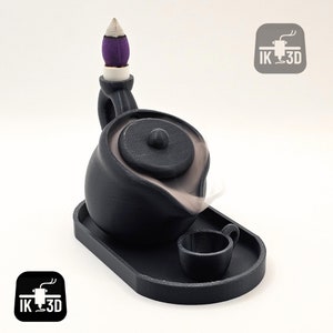 Peut inclure: Brûle-encens en céramique noire en forme de théière avec un couvercle et une petite tasse. Le brûle-encens est sur un plateau noir. Le brûle-encens est conçu pour créer un effet de fumée qui ressemble à de la vapeur sortant de la théière.