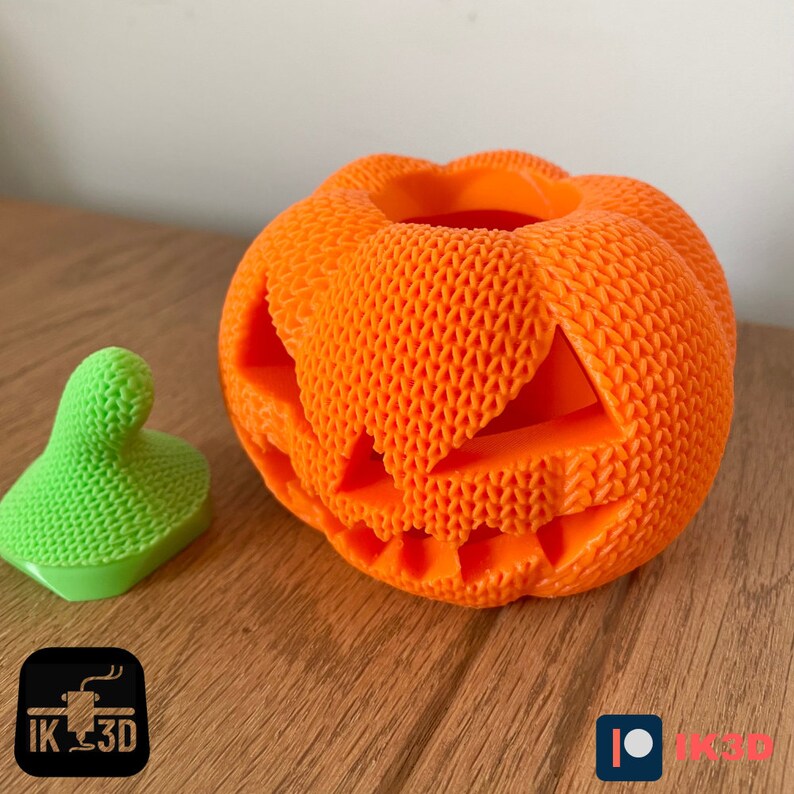 Pode incluir: Uma ab&oacute;bora laranja impressa em 3D com um rosto de ab&oacute;bora esculpido. A ab&oacute;bora tem uma superf&iacute;cie texturizada e est&aacute; sentada em uma superf&iacute;cie de madeira.