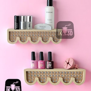 May include: Two decorative wooden shelves with a woven cane design, holding nail polish bottles, nail cleaner, and a nail file. The shelves have a scalloped edge and are against a pink background.