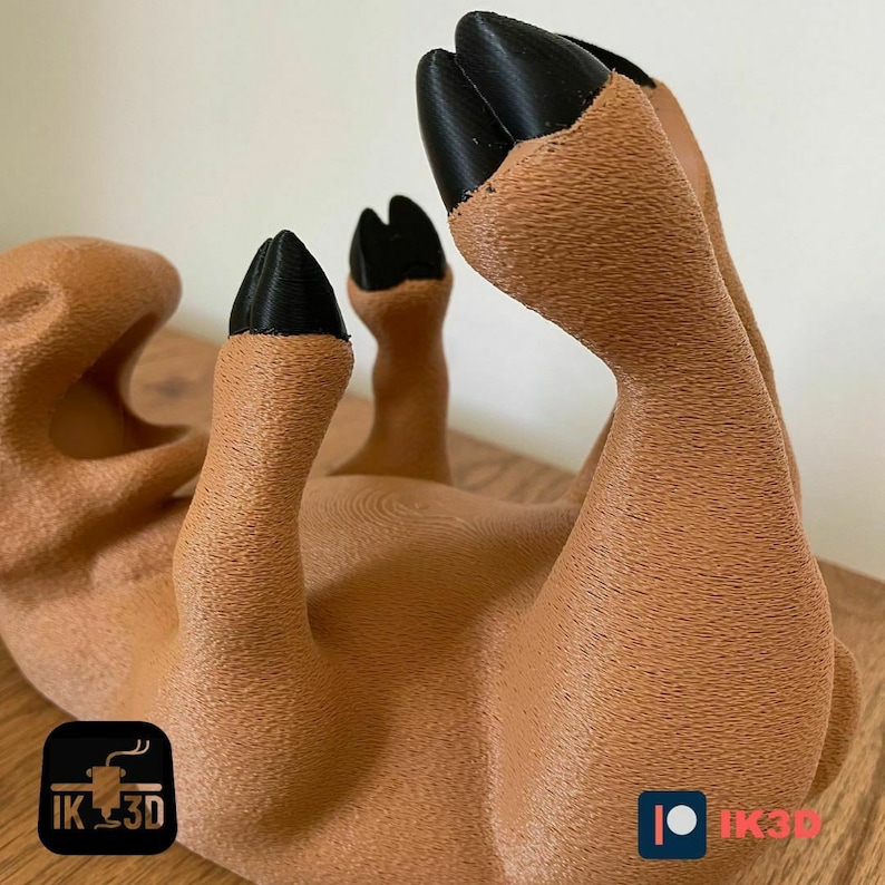 Puede incluir: Una figurita de ciervo de color marr&oacute;n impresa en 3D con pezu&ntilde;as negras. El ciervo est&aacute; acostado de espaldas con las patas en el aire.