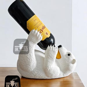 May include: White ceramic polar bear wine bottle holder with a bottle of red wine in its mouth. The bottle label reads "Rioja Odum", "Crianza", and "2020".