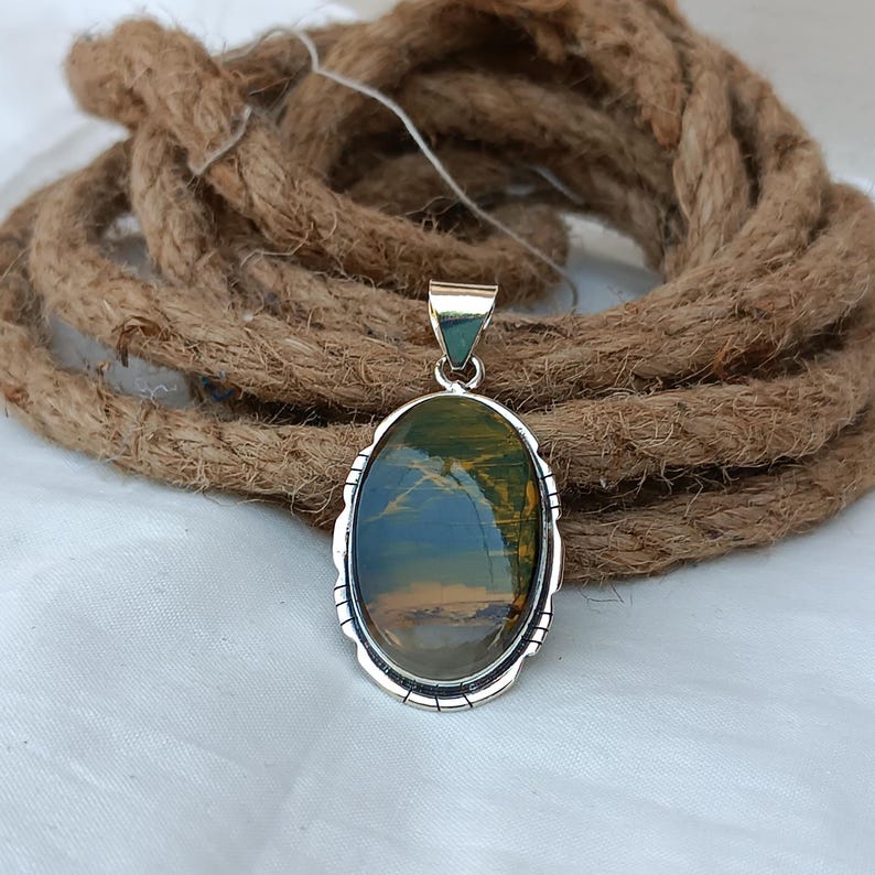 May include: An oval-shaped pendant with a green and brown tiger's eye stone set in a silver frame.