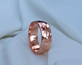 May include: A hammered copper ring with a wide band. The ring has a textured surface and a warm, reddish-brown color.