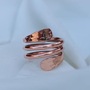 Peut inclure: Une bague en cuivre avec une finition martelée, tordue en forme de spirale. La bague est faite d'un seul fil de cuivre, et les extrémités sont jointes pour former une boucle continue.