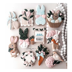 May include: A collection of Easter-themed biscuits, including bunny shapes, floral designs, and a market stall. The biscuits feature pastel colours, bows, and intricate details, creating a festive and decorative display. The biscuits are arranged on a white surface.