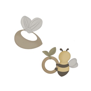 May include: A wooden ring with a bee and leaf design. The bee is yellow and black with brown wings. The leaf is green.
