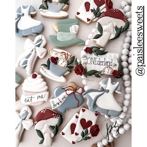 May include: A collection of Alice in Wonderland themed sugar cookies decorated with royal icing. The cookies feature images of Alice, the Mad Hatter, a teacup, a mushroom, playing cards, and a sign that says "ONEderland".