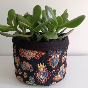 Peut inclure: Un pot en tissu noir avec un motif de cœurs colorés, rempli d'une plante succulente verte.