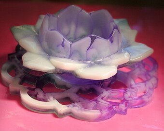 Puede incluir: Una flor de resina de color púrpura y blanco con un patrón de espiral. La flor es una pieza decorativa y tiene un centro hueco.
