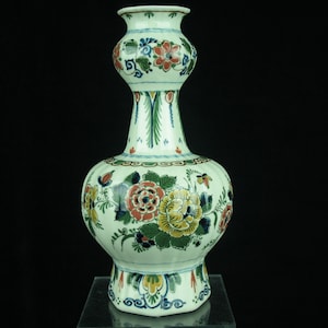 May include: A white ceramic vase with a bulbous body and a narrow neck. The vase is decorated with a colorful floral pattern in shades of blue, green, red, and yellow.