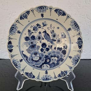 Może przedstawiać: Biały ceramiczny talerz z niebiesko-białym wzorem kwiatowym i ptakiem. Talerz ma falisty brzeg.