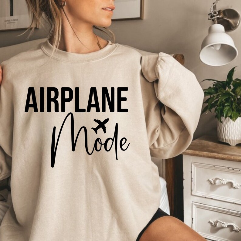 May include: A beige sweatshirt with the text "AIRPLANE Mode" in black lettering and a small airplane graphic.
