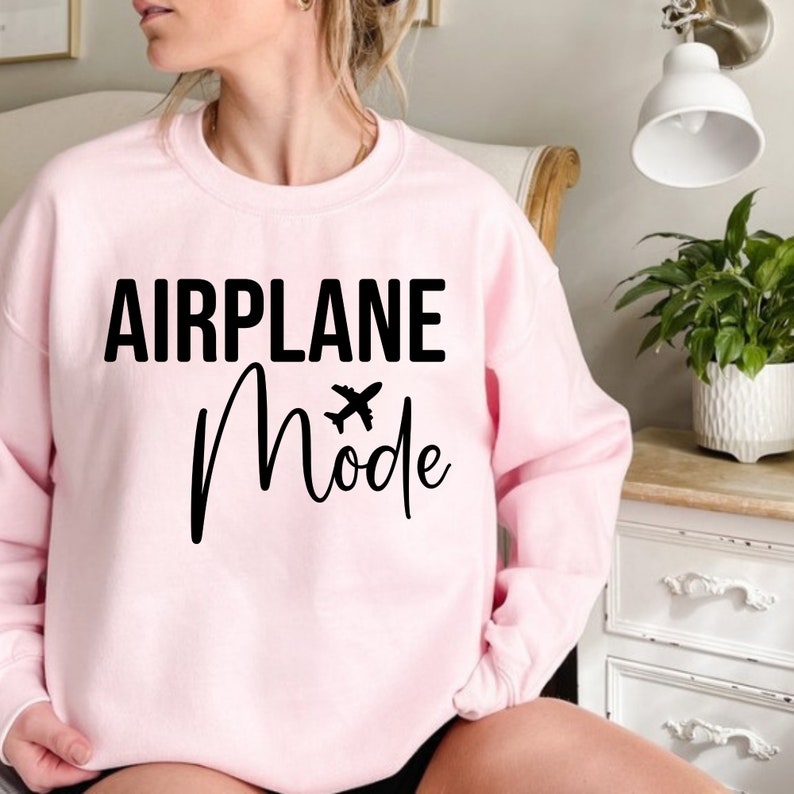 May include: A pink sweatshirt with the text "AIRPLANE Mode" in black lettering. A small airplane icon is above the word "Mode".