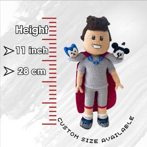May include: Crocheted plush toy of a person wearing a red cape and holding two smaller plush toys. The person is 11 inches tall or 28 cm. Custom sizes are available.