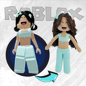 May include: A crocheted doll with brown hair and a light blue outfit, standing next to a digital avatar with the same outfit. The text "ROBLOX" is visible in the background.