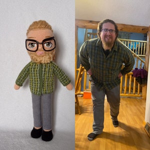 May include: A crocheted doll with a green and yellow plaid shirt, gray pants, and brown hair. The doll has a beard and is wearing glasses. The doll is standing next to a photo of a person wearing a similar plaid shirt.