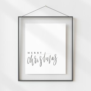 May include: A black framed print with the text "Merry Christmas" in a handwritten font.