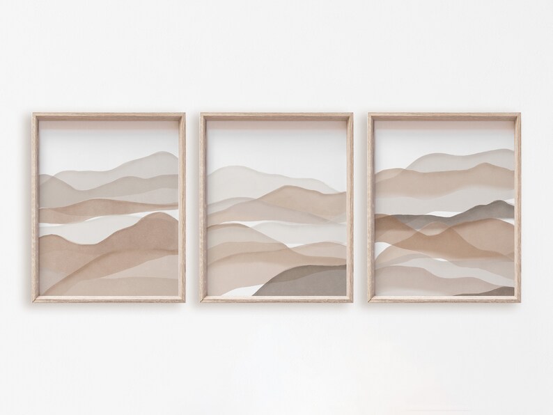 May include: Three framed prints with abstract watercolor-style landscapes in shades of brown and beige. The prints are arranged in a row, with the frames aligned.