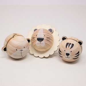 May include: Three wooden toy animal heads, a monkey, a lion, and a tiger. The monkey and tiger are round and the lion is a flat head with a mane.