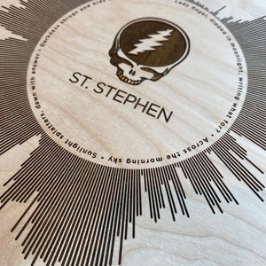 May include: A wooden wall art piece with a circular design featuring a Grateful Dead logo and the song title "St. Stephen". The design is surrounded by lyrics from the song.