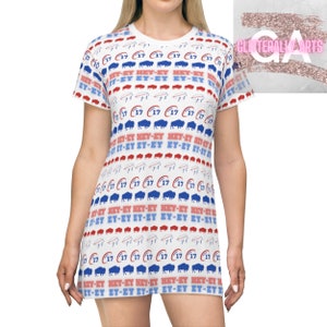 Può includere: Abito t-shirt bianco con un motivo ripetuto di silhouette di bufali blu e rossi, il numero "17" e il testo "HEY-EY".