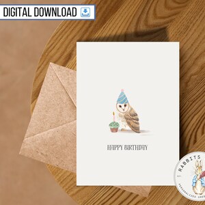 Peut inclure: Une carte d'anniversaire illustrant un hibou en aquarelle portant un chapeau de fête bleu et tenant un cupcake avec une bougie allumée. La carte porte le texte "Joyeux anniversaire" imprimé dessus.