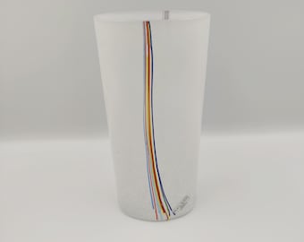 May include: A clear glass tumbler with a white speckled finish and a single vertical line of colourful stripes. The glass has the word "Kosta Boda" printed on the bottom.