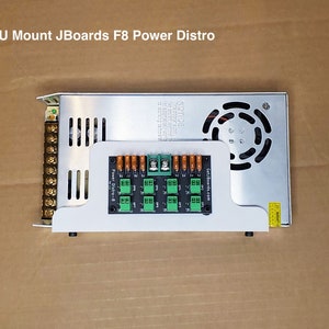 Peut inclure: Un support d'alimentation argenté avec une carte de distribution d'alimentation noire et verte. La carte comporte plusieurs connecteurs verts et le texte "Power Distro-8". Le texte "PSU Mount JBoards F8 Power Distro" est en haut.
