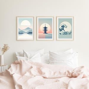 Könnte beinhalten: Drei gerahmte Kunstdrucke mit japanischem Thema. Die Drucke zeigen eine Berglandschaft, eine Pagode und eine Welle, alle in einem minimalistischen Stil mit sanften Farben. Die Rahmen sind aus hellem Holz.
