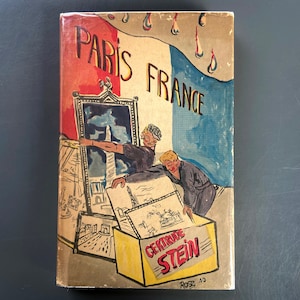 May include: A vintage book cover with a colorful illustration of two people holding up a postcard with a drawing of the Eiffel Tower. The cover features the text "Paris France" and "Centre Stein" in a yellow box.
