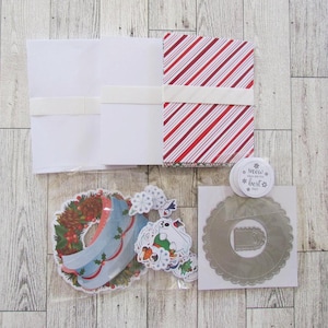 May include: A stationery set featuring white envelopes, a stack of red and white candy cane striped cards, a plastic bag of die-cut Christmas wreath and polar bear stickers, and a silver scalloped card with a sticker reading snow days are the best.