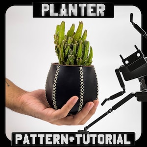 Puede incluir: Un macetero de cuero negro con costuras blancas contiene una pequeña planta de cactus. El macetero está siendo sostenido por una mano. El texto "PLANTER PATTERN+TUTORIAL" se muestra en letras blancas sobre un fondo negro.