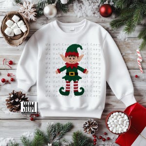 Peut inclure: Sweat-shirt blanc avec un motif d'elfe coloré. L'elfe porte un chapeau vert, un nœud papillon rouge et des jambes rayées. Les mots "Do Not Copy" sont imprimés sur le sweat-shirt. Vêtement de Noël festif.