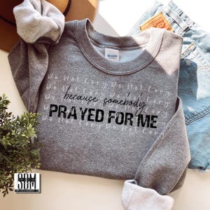 May include: Gray sweatshirt with the text "Do Not Copy Do Not Copy because somebody PRAYED FOR ME" printed in black.